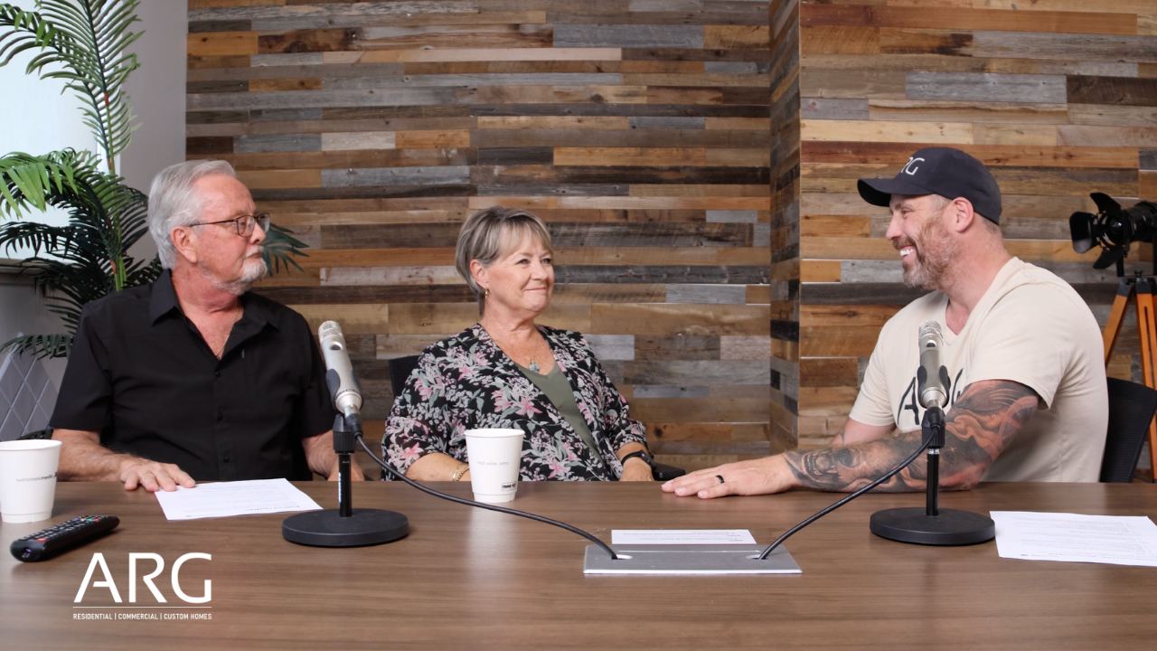 Don and Gail Jones sitting at a podcast table with Adam Galbraith of ARG Contracting, mid-conversation, in a studio with a reclaimed wood accent wall.